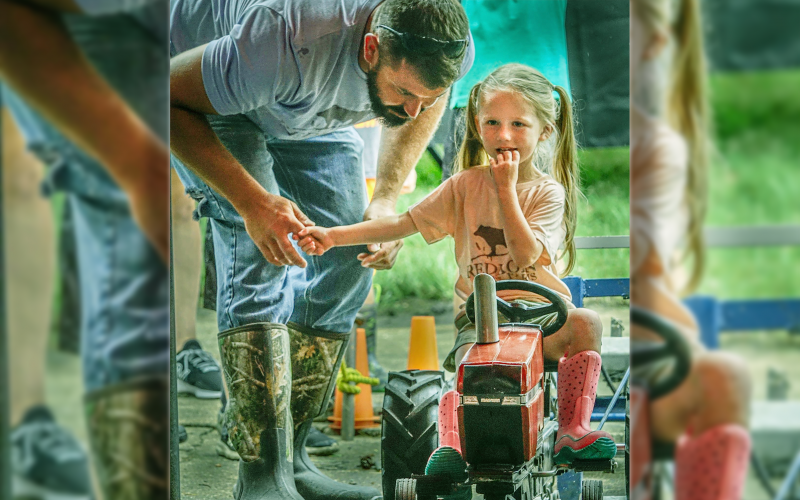 NATHAN PARMENTIER offers some encouragement to his daughter, Riley Parmentier, trying to decide on the tractor pull competition.